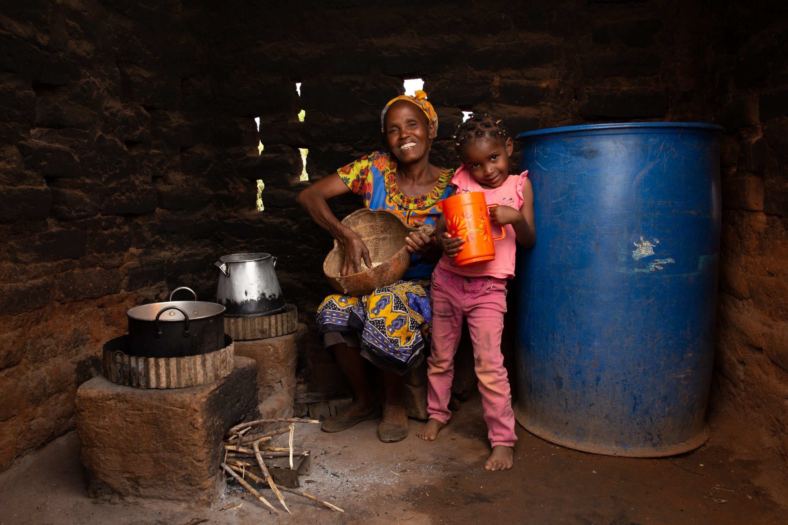 A smiling Kenyan woman and her daughter use their new Bridge Carbon cookstove